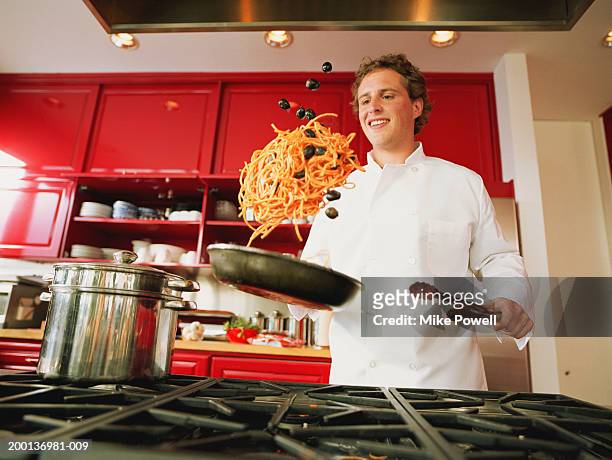 chef tossing spaghetti and olives from pan - lanzar actividad física fotografías e imágenes de stock