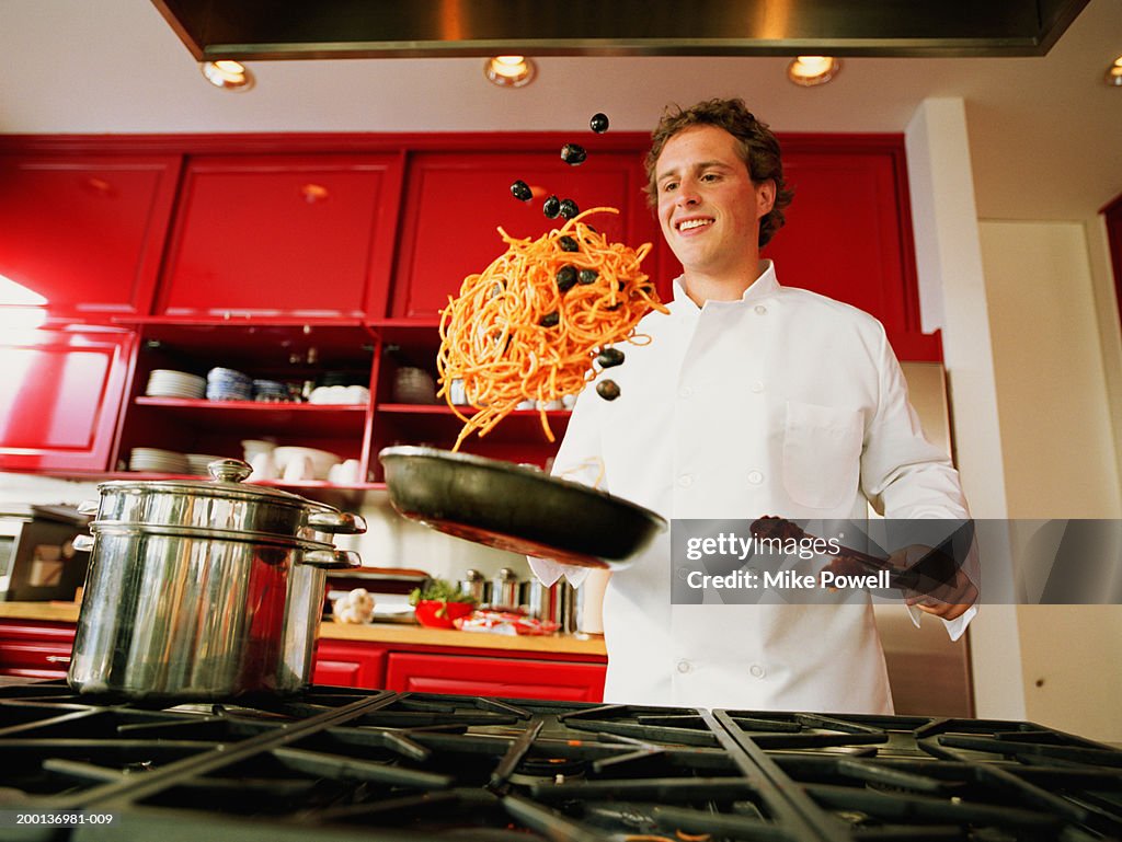 Chef tossing spaghetti and olives from pan