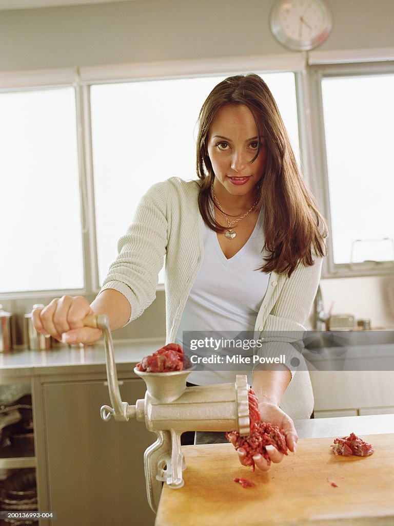 Woman using meat grinder in kitchen