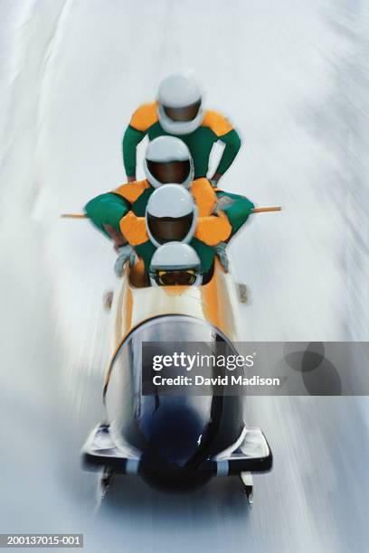 four man bobsled team mounting their sled (blurred motion) - bobsleigh team stock-fotos und bilder