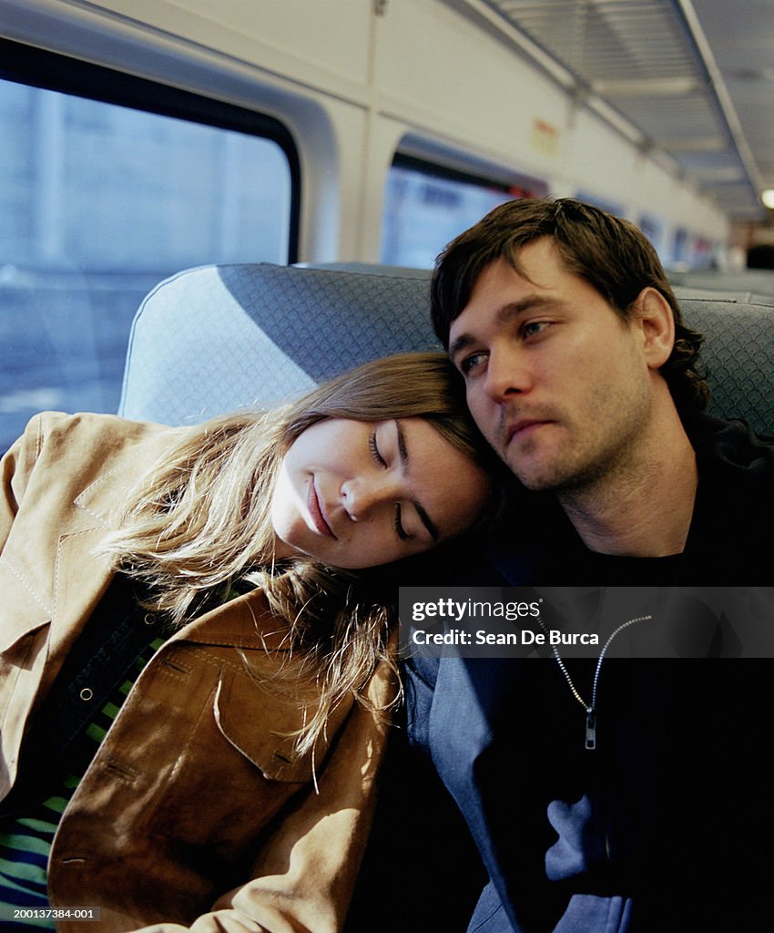 Couple on train, woman resting head on man's shoulder