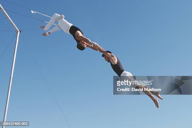 two male trapeze artists performing, outdoors - trapeze stock-fotos und bilder