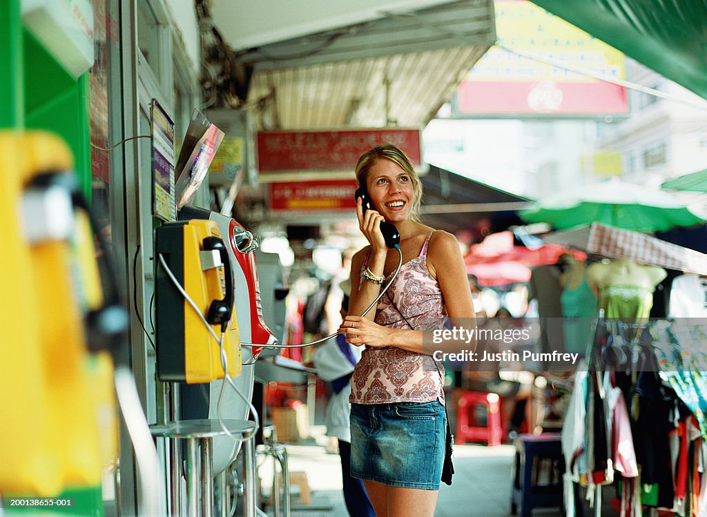 Thailand, Bangkok, young woman using public telephone