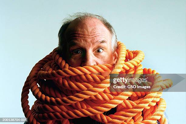 senior man with rope wrapped around shoulders and neck, portrait - tied up rope stock pictures, royalty-free photos & images