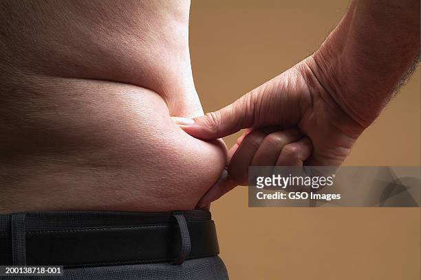 bare-chested senior man pinching skin around waist, mid section - fat ストックフォトと画像