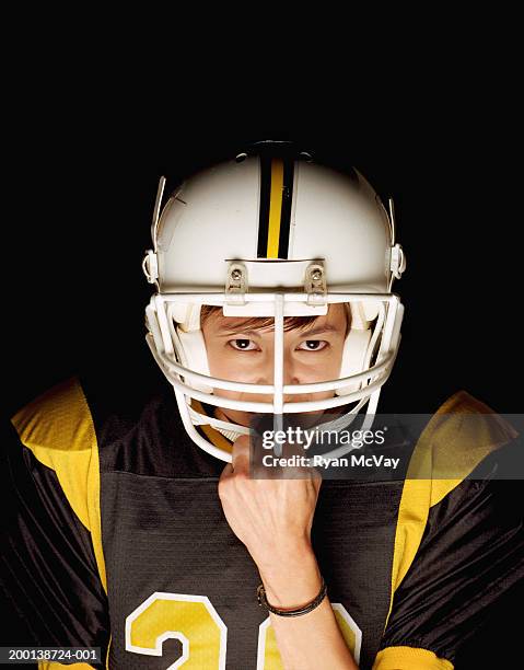 young female football player grasping helmet guard, portrait - american football strip stock pictures, royalty-free photos & images