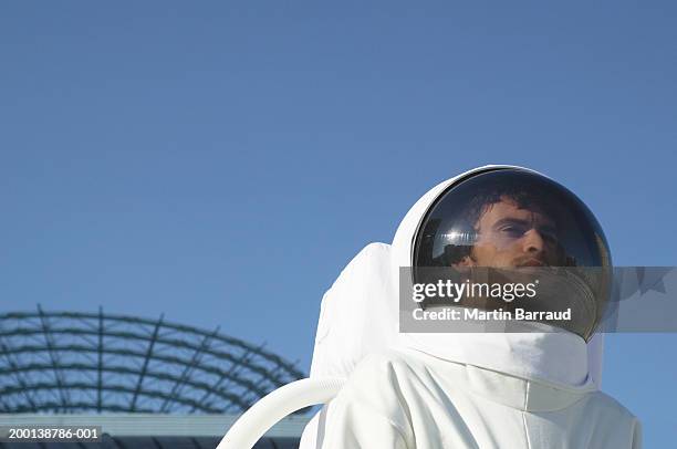 astronaut wearing helmet, satellite dish in background, low angle view - astronaut potrait stock-fotos und bilder
