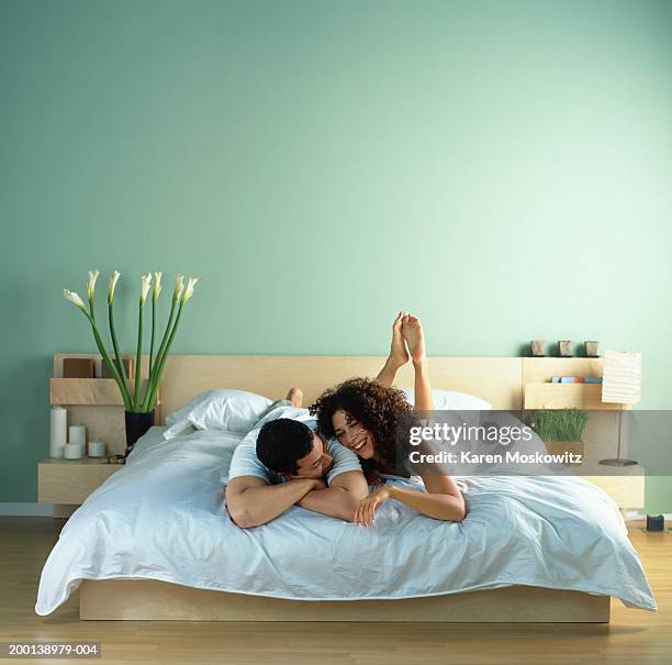 young couple lying on bed together - cama de matrimonio fotografías e imágenes de stock