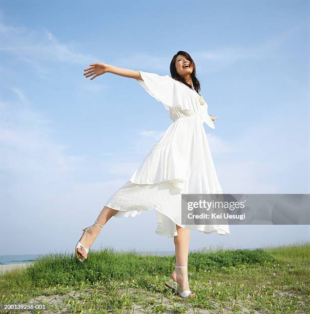 young woman in white dress, dancing on beach - weißes kleid stock-fotos und bilder