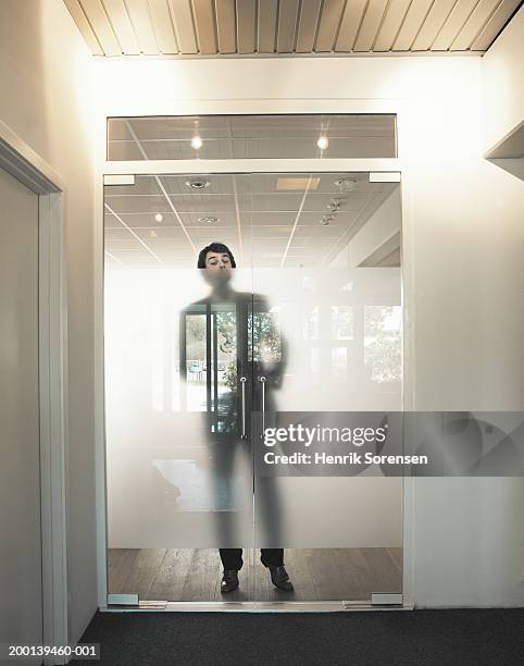 man standing behind transparent reflecting doors, portrait - suspicion office stock pictures, royalty-free photos & images