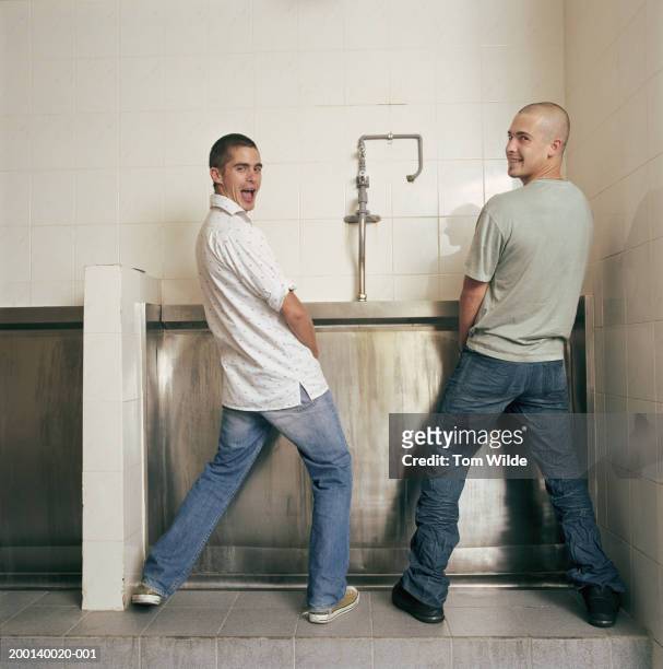 two young men at urinal, looking over shoulders, portrait - man looking back stock pictures, royalty-free photos & images