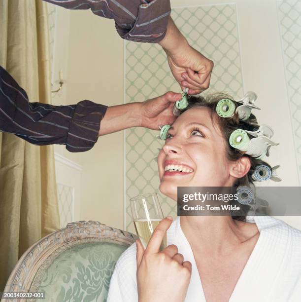 woman having hair put in rollers, holding champagne flute, looking up - wedding preparation stock pictures, royalty-free photos & images