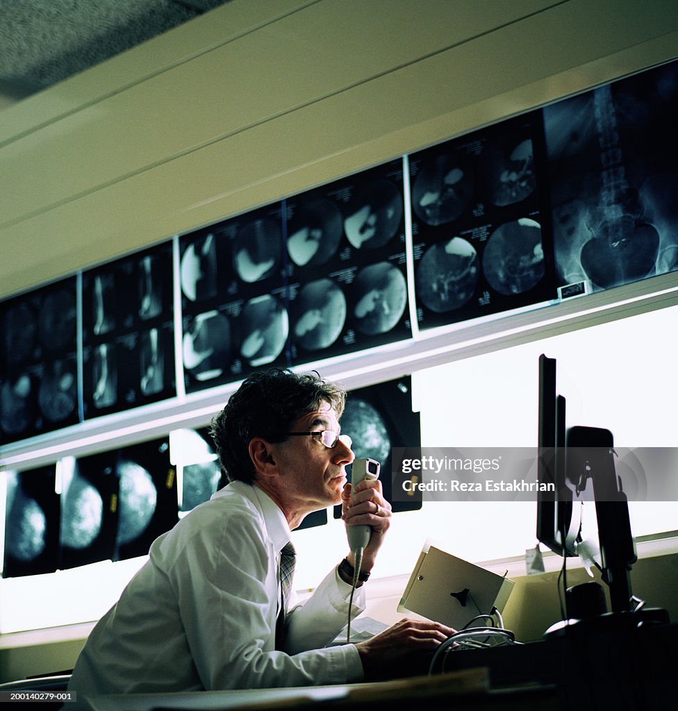 Radiologist looking at computer screen, x-rays in background