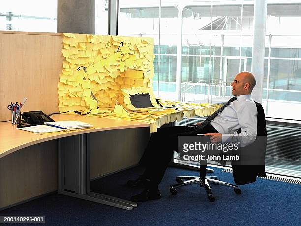 man sitting at desk covered in yellow memo notes - cubicle work stock-fotos und bilder