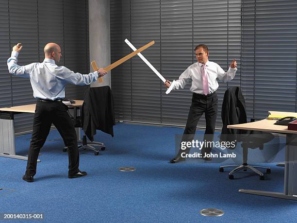 two men in office, play sword fighting using large rulers - sword photos et images de collection