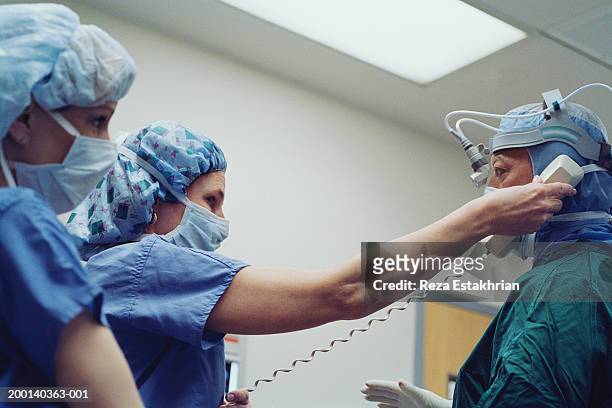 Nurses in scrubs, one hold telephone to surgeons ear