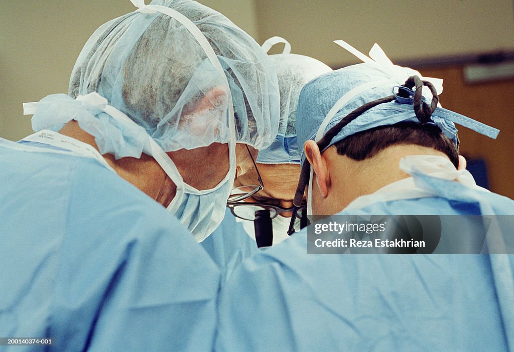 Three surgeons operating on heart, upper section, rear view