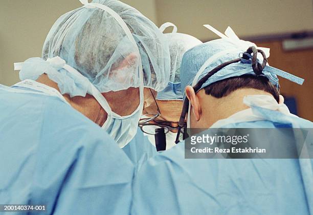 three surgeons operating on heart, upper section, rear view - heart surgery stock pictures, royalty-free photos & images