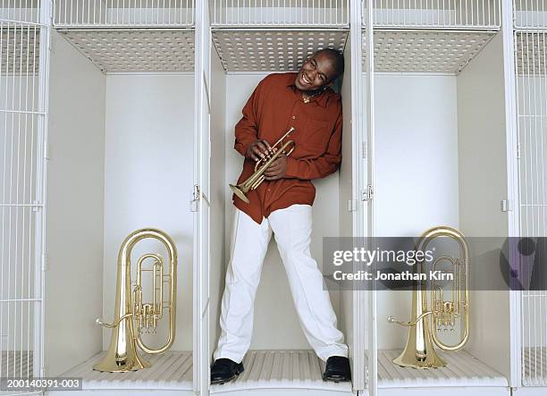 young man holding trumpet crammed into music instrument storage locker - self storage red stock pictures, royalty-free photos & images