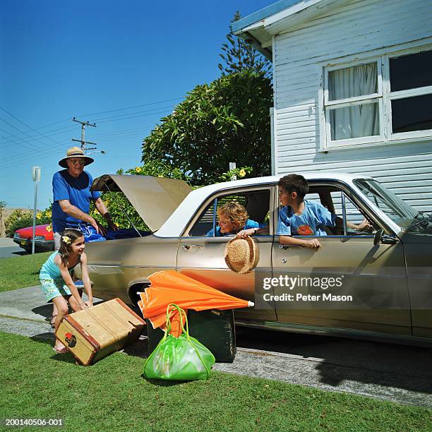 man and girl (6-8) loading luggage in car, woman and boy (6-8) in car - car sunshade stock pictures, royalty-free photos & images