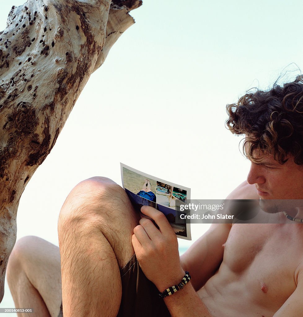 Young man writing postcard by tree