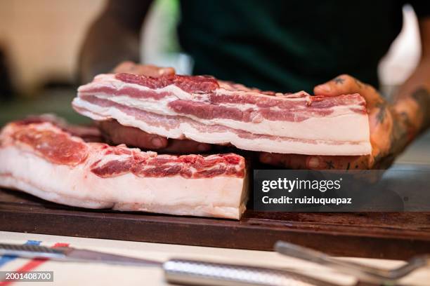 big piece of iberian bacon on a wooden board - adding salt stock pictures, royalty-free photos & images