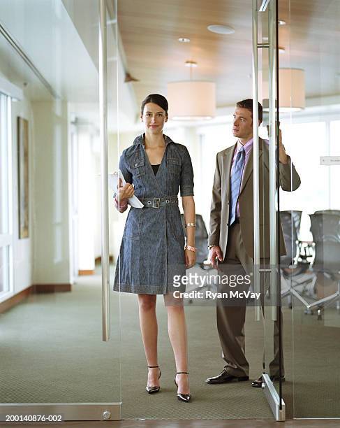 businessman holding conference room door for businesswoman - gallanterie stock-fotos und bilder