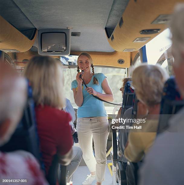 woman holding microphone on bus with passengers (focus on woman) - guide touristique photos et images de collection