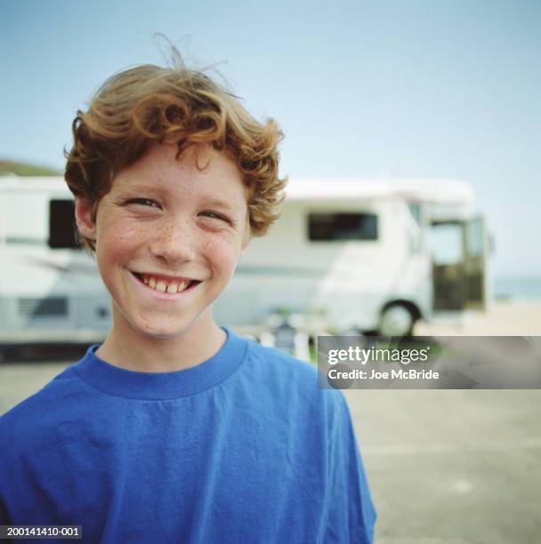 boy (9-11) with freckles, smiling, rv in background, portrait - lentiggine foto e immagini stock