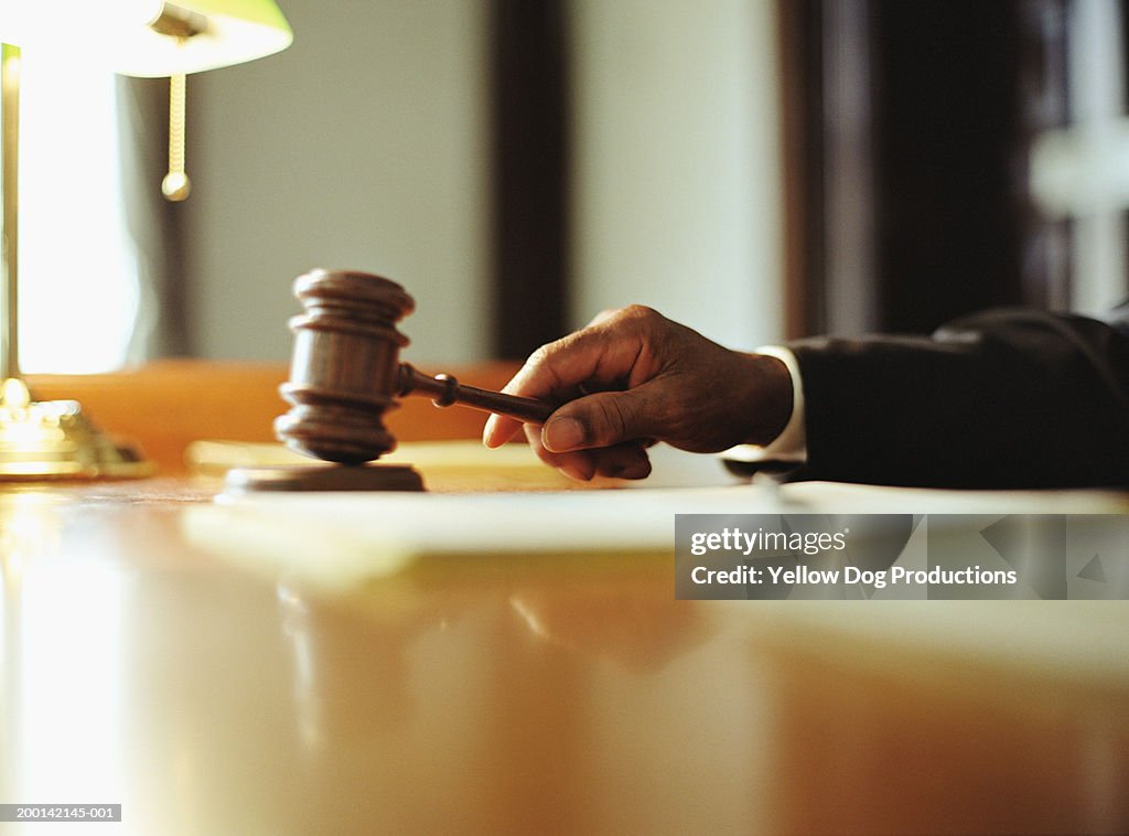 Male judge striking gavel in courtroom, close-up