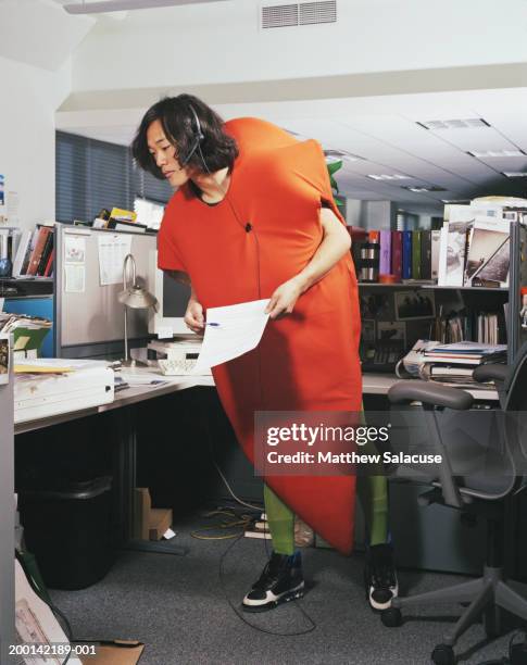 young man wearing carrot costume in office - carrot costume stock pictures, royalty-free photos & images
