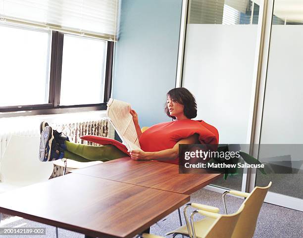 young man wearing carrot costume in office, reading newspaper - man in costume stock pictures, royalty-free photos & images