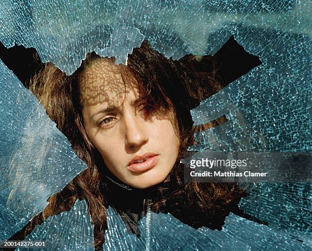 young woman looking through pane of shattered glass, close-up - broken window stock pictures, royalty-free photos & images