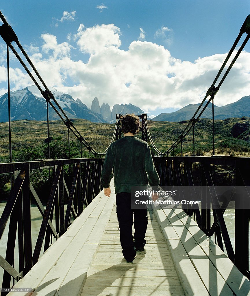 Chile, Patagonia, young man crossing footbridge, rear view