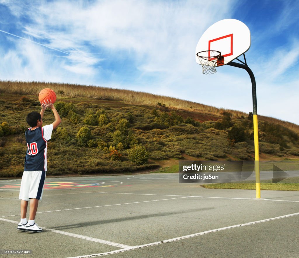 Boy (9-1) preparing to shoot basketball, rear view