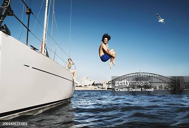 australia, sydney, young man jumping from boat in to harbour - australia holiday stock-fotos und bilder