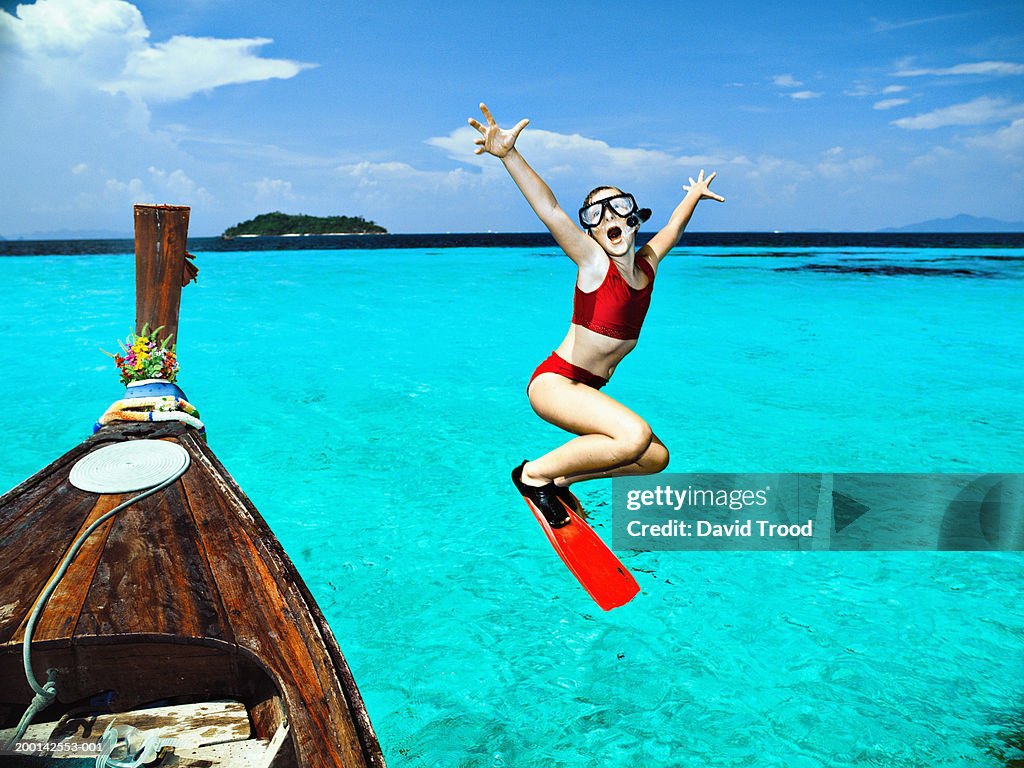 Girl (9-11) jumping from longtail boat into sea