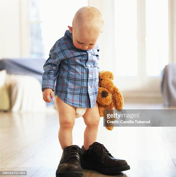 Baby Boy Standing In Adults Shoes Holding Stuffed Toy High-Res Stock Photo  - Getty Images