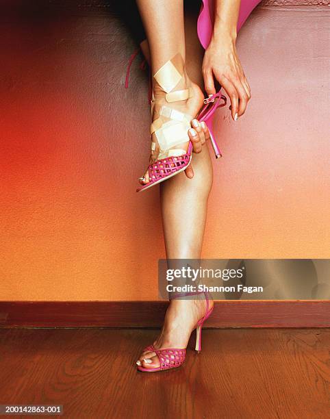 woman putting on shoes with bandages on foot - high heel stockfoto's en -beelden
