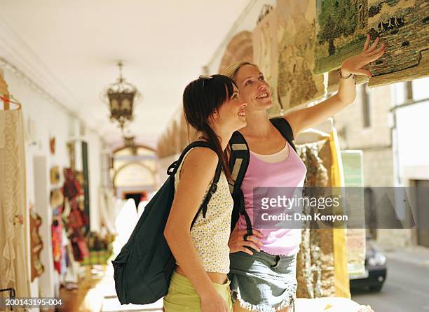 two young women browsing in shop, looking at tapestries - andalusia stock-fotos und bilder