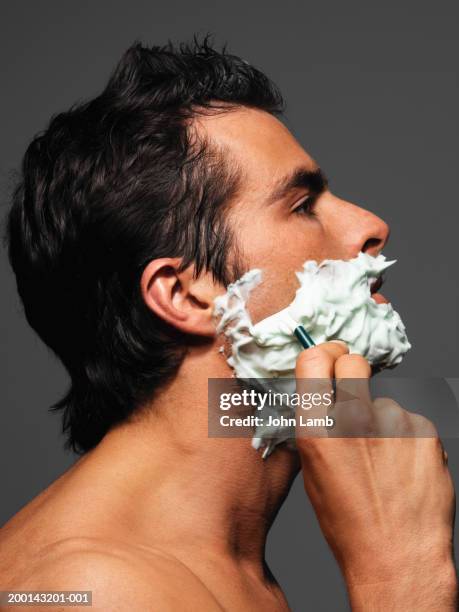 young man shaving, profile - man shaving face stock-fotos und bilder