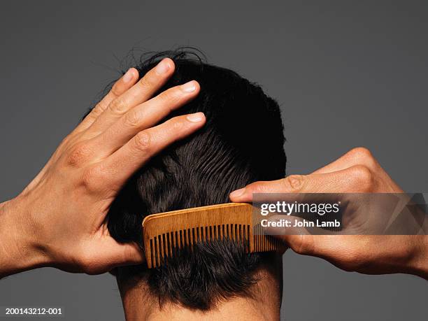 young man combing back of head, rear view - peinar fotografías e imágenes de stock