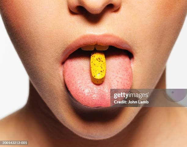 young woman with pill on tongue, close-up - tomada de decisão imagens e fotografias de stock