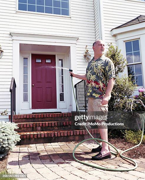 man hosing down front door, looking away - idiots fotografías e imágenes de stock