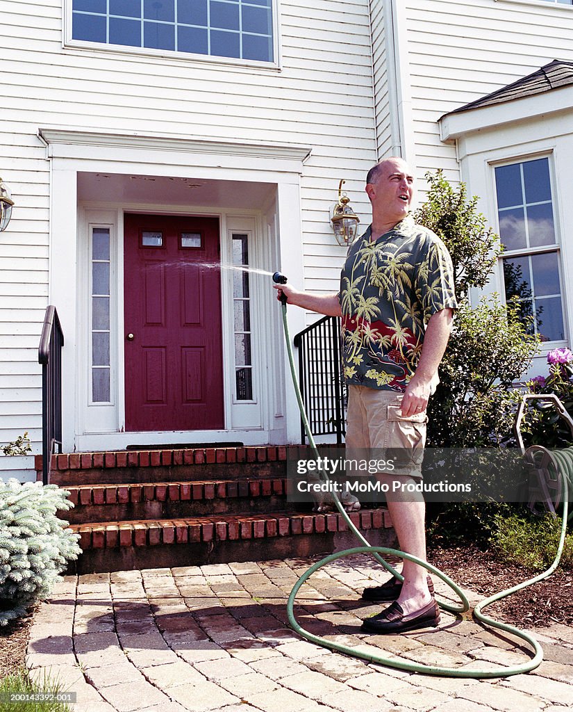 Man hosing down front door, looking away