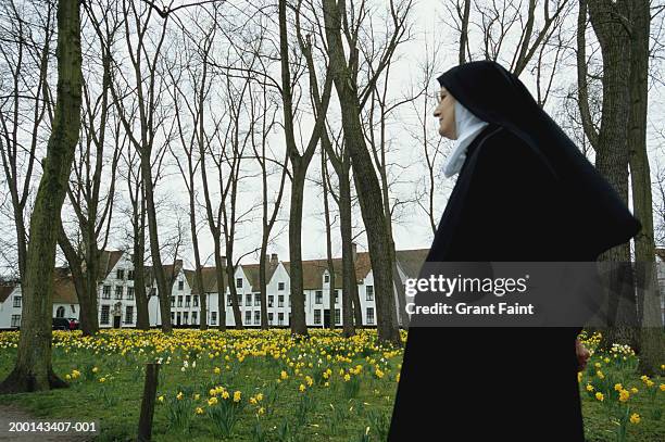 nun walking in field, buildings in background - nun habit stock pictures, royalty-free photos & images