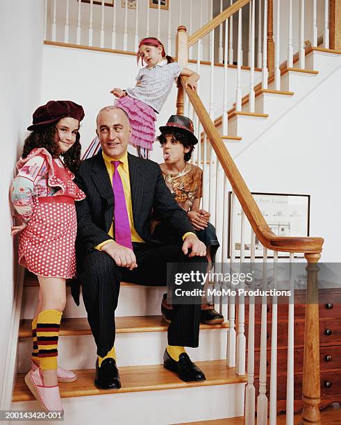 father and children (5-12) on staircase, boy sticking out tongue - quirky family stock-fotos und bilder