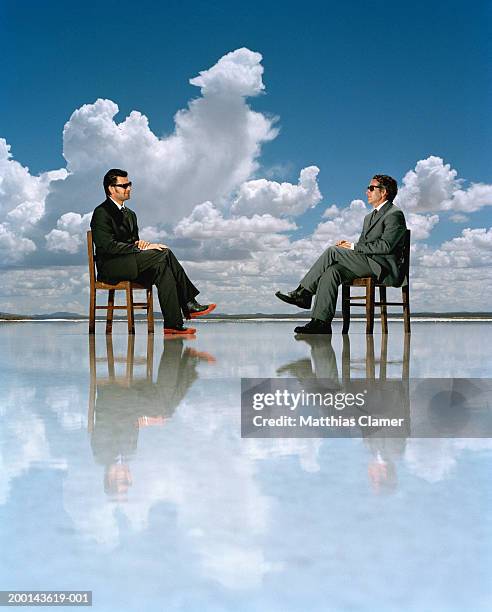 two businessmen sitting on chairs on salt flat, side view - 背広 ストックフォトと画像