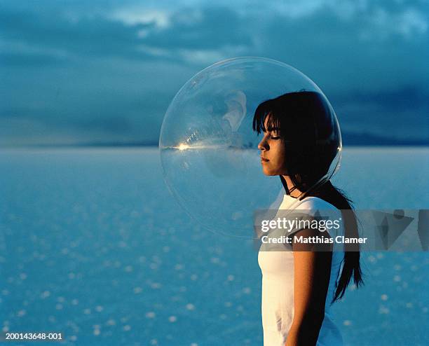young woman wearing protective bubble over head, side view - people inside bubbles stock-fotos und bilder