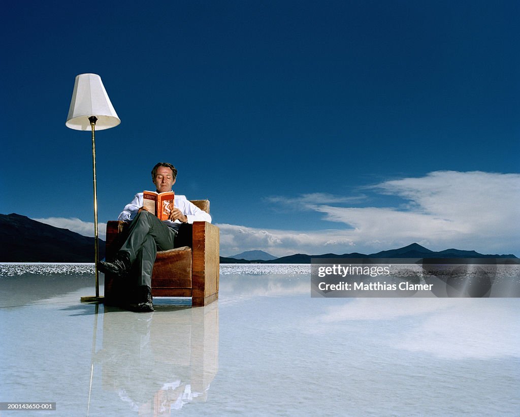 Mature man reading book on salt flat